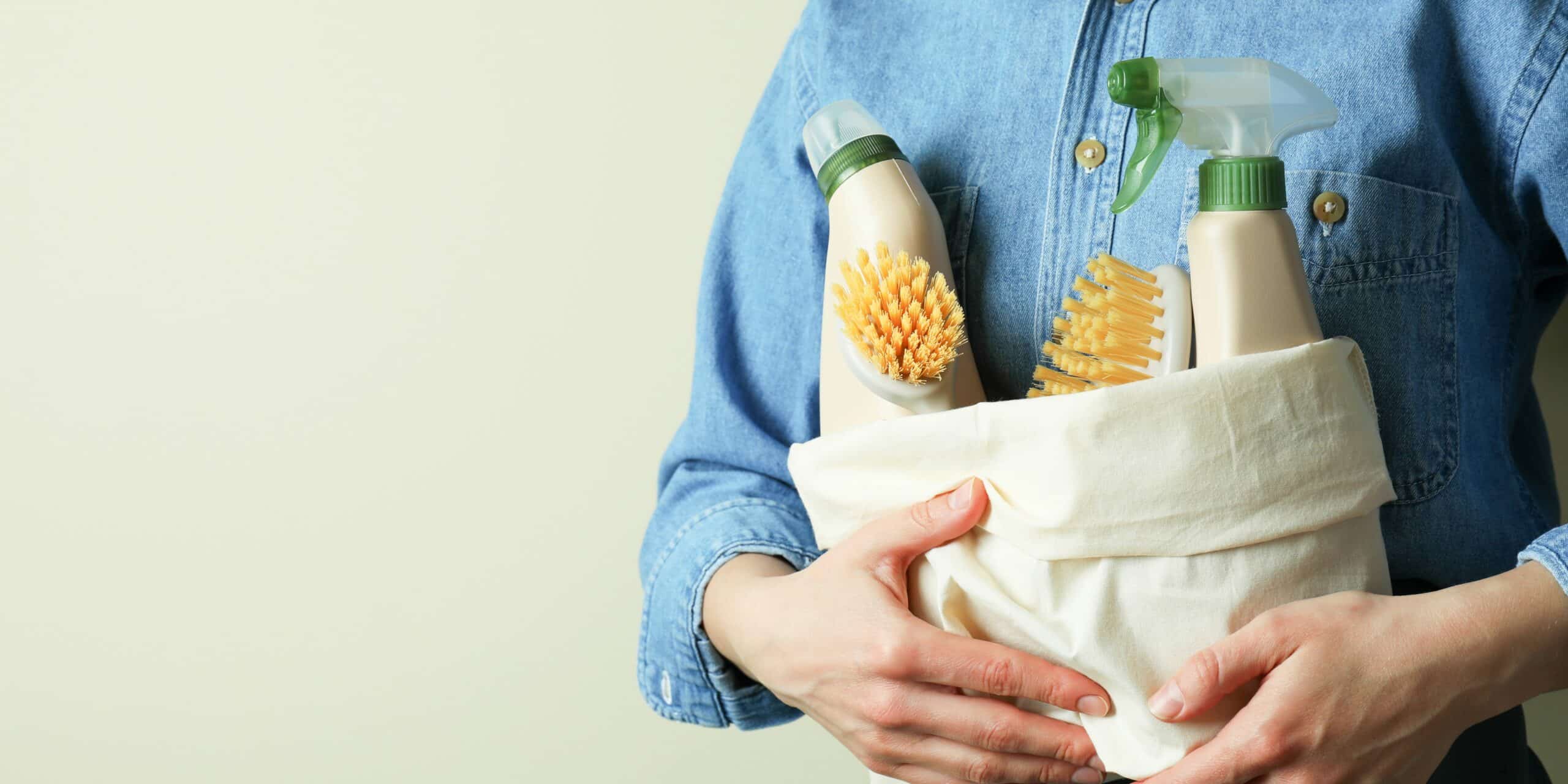 Picture of a lady holding a basket with cleaning materials.