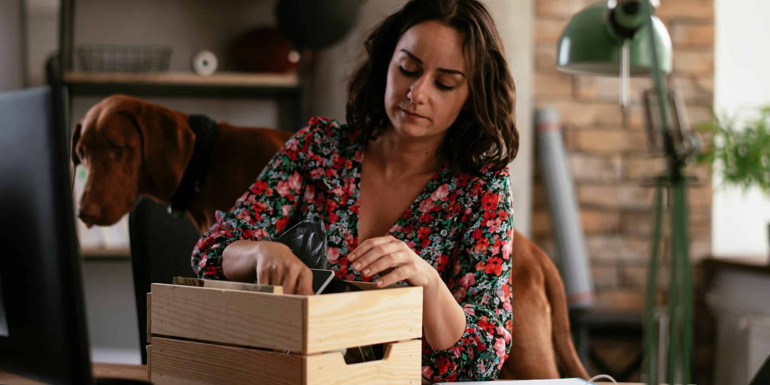 A woman boxing her valuables with her pet dog at her back.