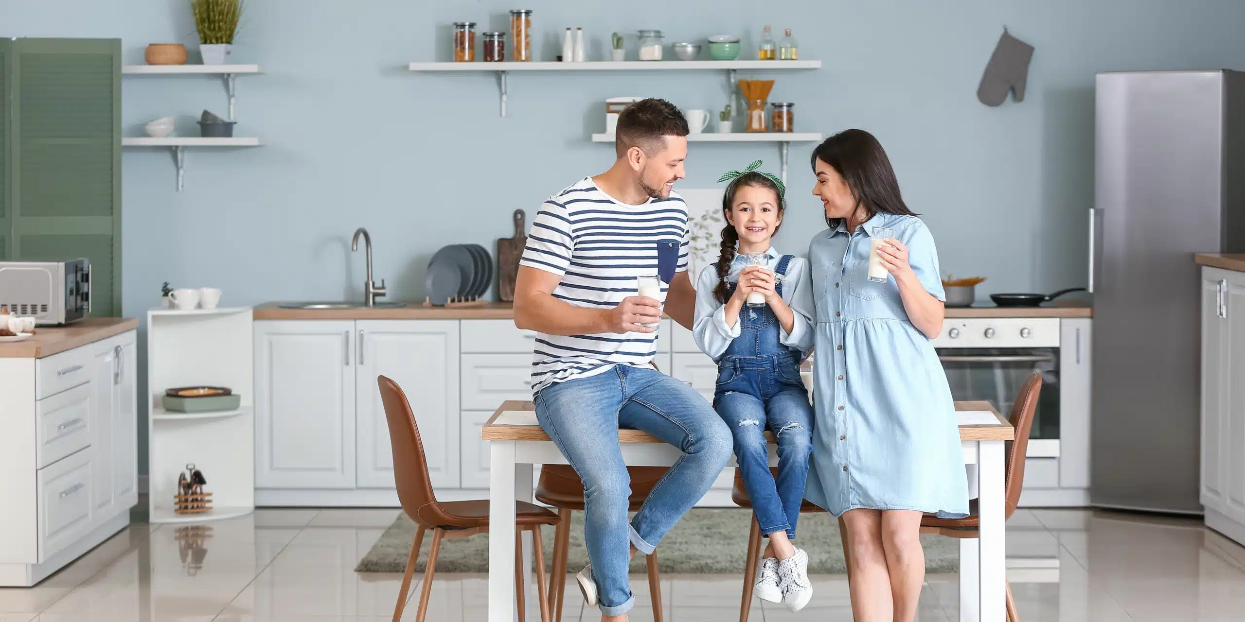 A happy family of 3 in the kitchen with a glass of milk.